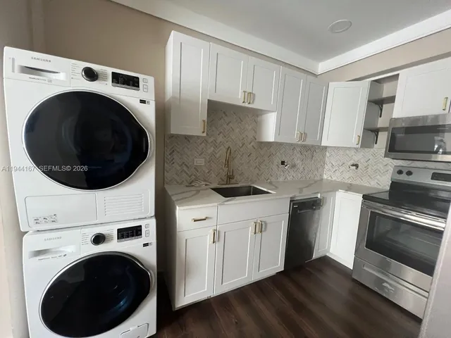a kitchen with stainless steel appliances sink a washer and dryer