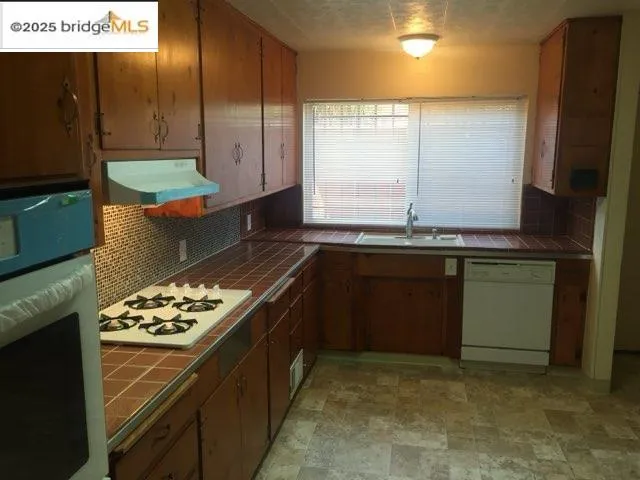 a kitchen with kitchen island stainless steel appliances a sink stove and window
