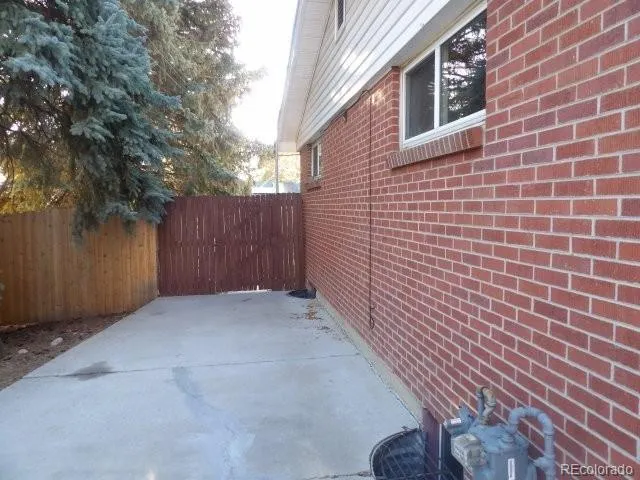 a view of backyard with brick wall and a large tree