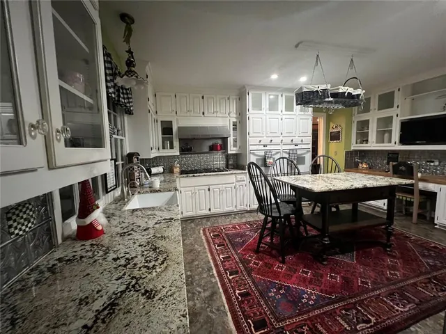 a kitchen with stainless steel appliances granite countertop a stove a sink dishwasher a dining table and chairs with wooden floor