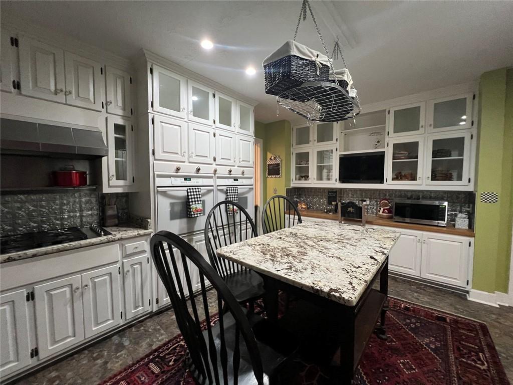 1710 Country Club Road Eufaula, AL 36027 - Photo 33 of 44 a kitchen with stainless steel appliances granite countertop a stove a sink dishwasher a dining table and chairs with wooden floor