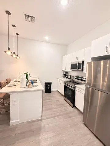 a kitchen with stainless steel appliances a stove a sink a microwave and refrigerator