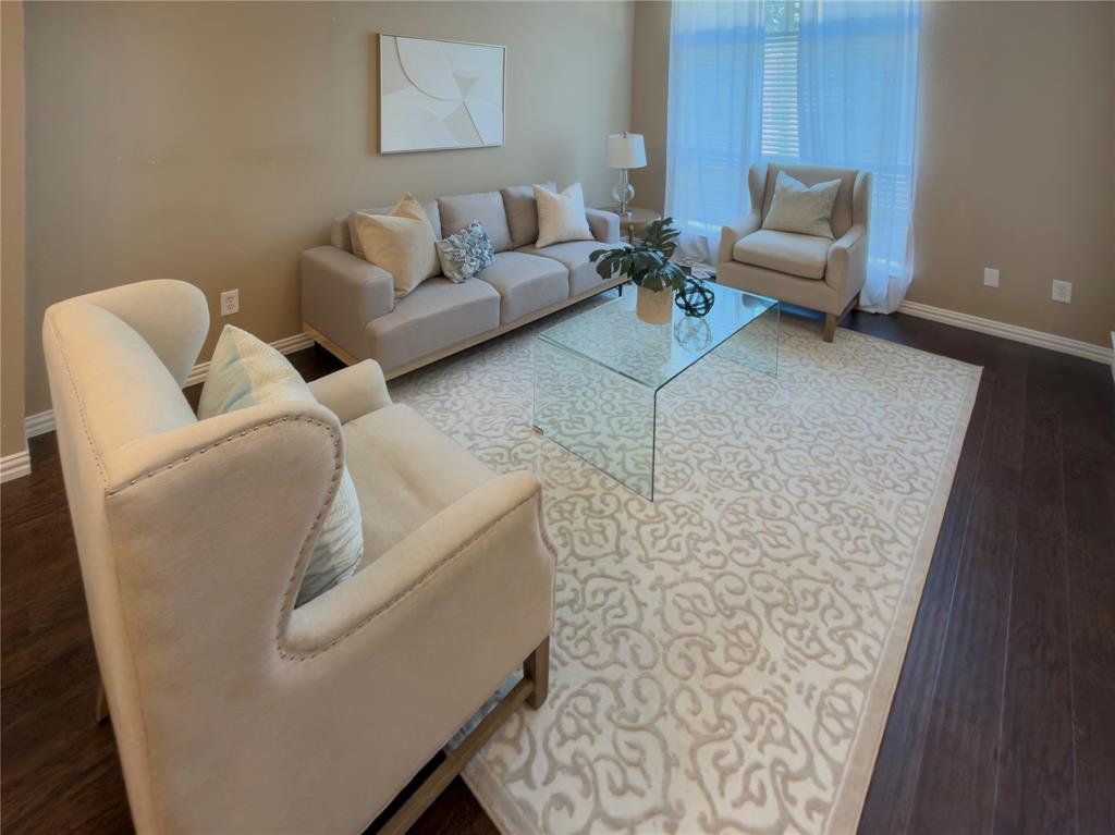 4234 Timberglen Road Dallas, TX 75287 - Photo 4 of 30 Dark wood-finish flooring, light tan wall color, large window with sheer white drapery, and a clear glass coffee table
