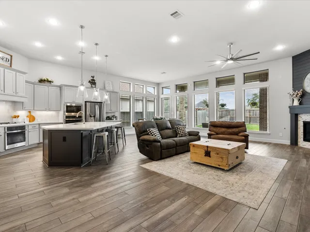 a living room with stainless steel appliances kitchen island granite countertop a couch and wooden cabinets