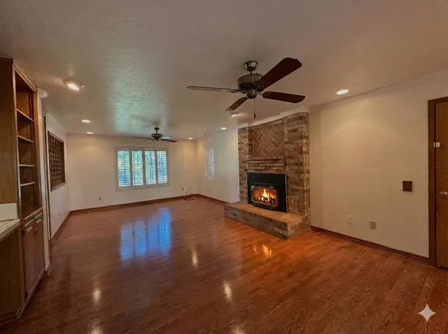 an empty room with wooden floor a fireplace and windows