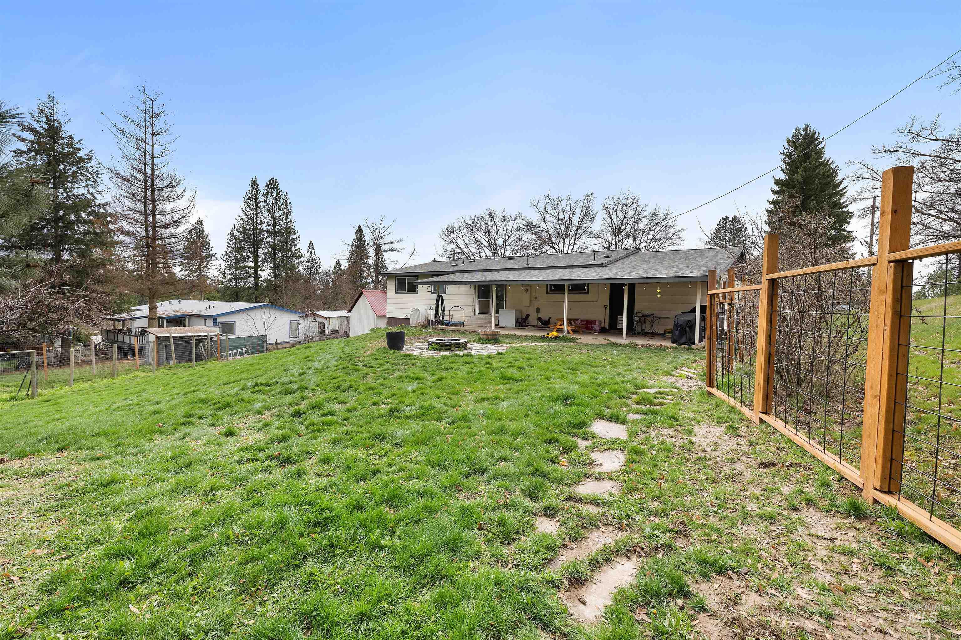 604 Line Street Deary, ID 83823 - Photo 26 of 28 Back of property with a fire pit, a fenced backyard, a patio, and a shingled roof