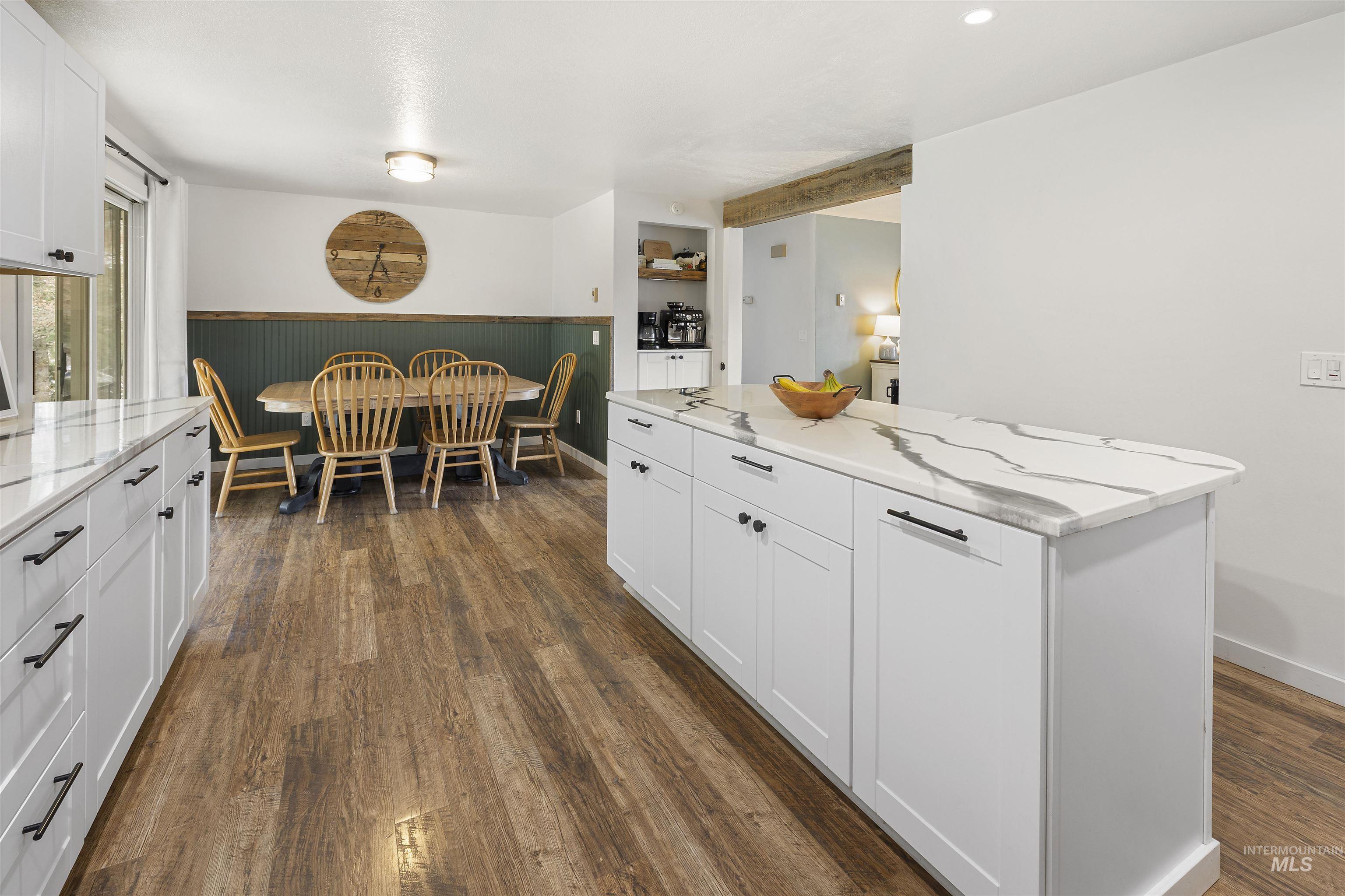 604 Line Street Deary, ID 83823 - Photo 4 of 28 Kitchen with white cabinets, a wainscoted wall, light stone counters, a center island, and dark wood finished floors