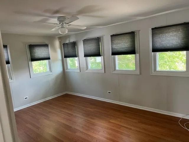 a view of an empty room with wooden floor and windows