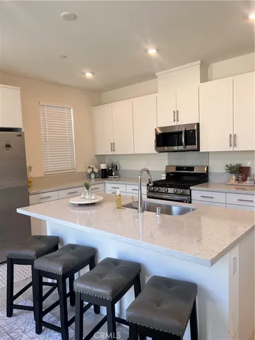 a kitchen with stainless steel appliances a stove a sink a microwave a dining table and chairs