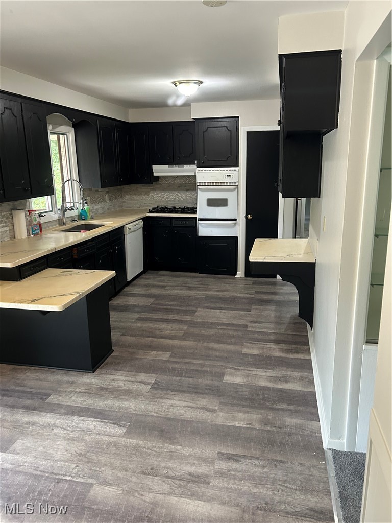 8223 Montello Road Independence, OH 44131 - Photo 13 of 28 Kitchen with dark cabinets, light countertops, oven, dark wood-type flooring, and tasteful backsplash