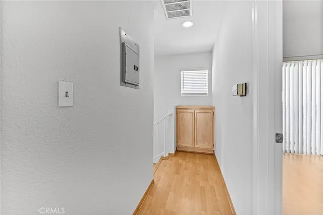 a view of a hallway with wooden floor and a bathroom