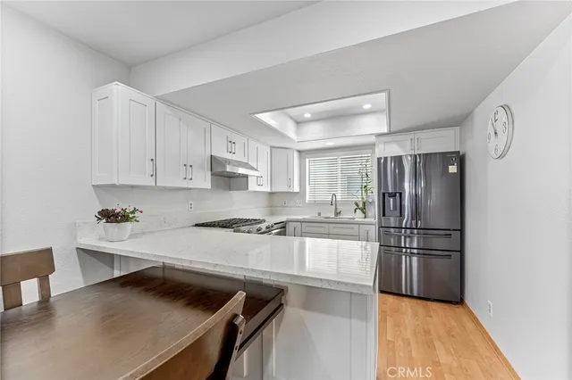 a kitchen with a refrigerator a stove and white cabinets with wooden floor