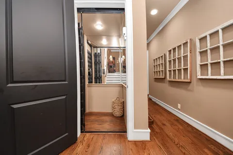 a view of a hallway with wooden floor and a living room