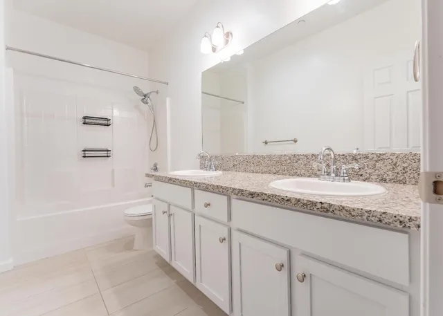 a bathroom with a granite countertop sink a toilet and shower