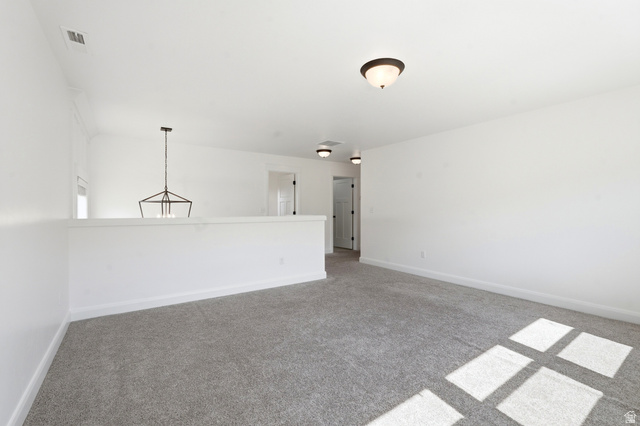 338 Windy Rdg Drive Smithfield, UT 84335 - Photo 21 of 63 Spacious carpeted room featuring a partial wall, a geometric chandelier, and multiple doors