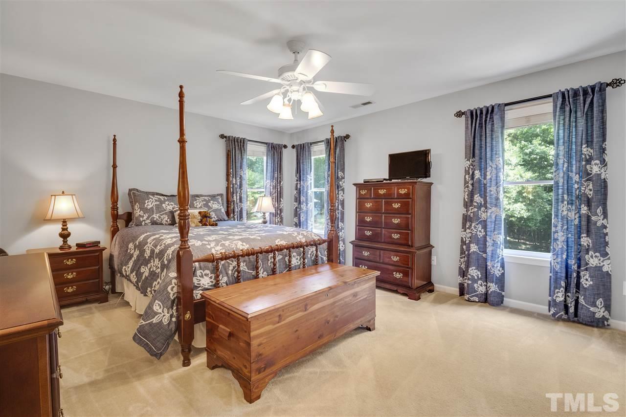 10228 River Bank Drive Raleigh, NC 27614 - Photo 12 of 29 a bedroom with a bed a chandelier and a flat tv screen