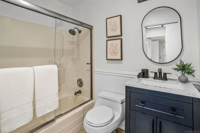 a bathroom with a granite countertop toilet a sink and a mirror