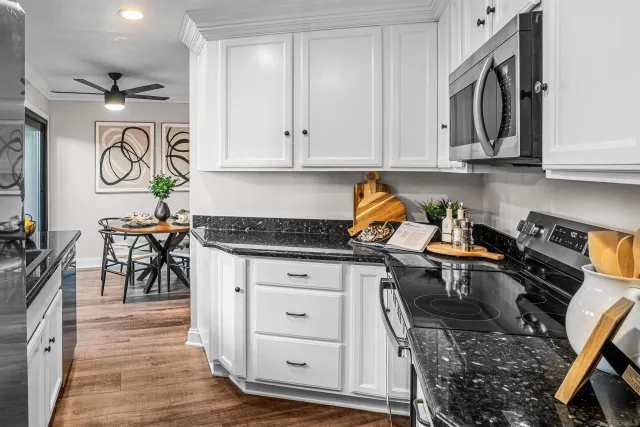 a kitchen with stainless steel appliances granite countertop a stove and white cabinets