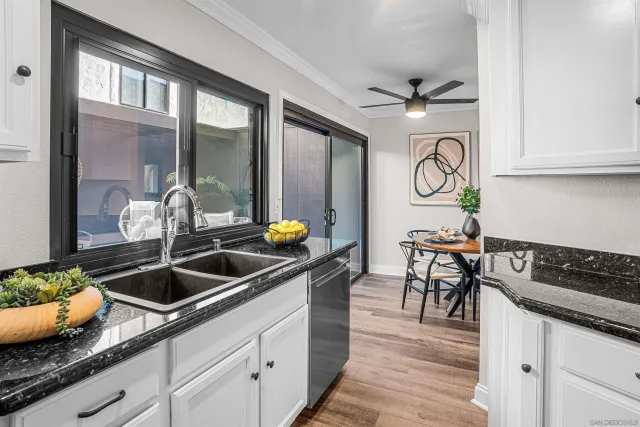 a kitchen with granite countertop a sink a stove and white cabinets