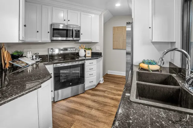 a kitchen with granite countertop a stove sink and cabinets