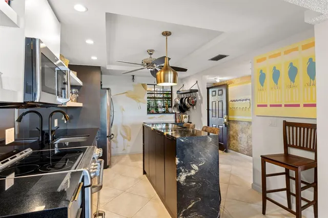 a kitchen with stainless steel appliances kitchen island granite countertop a stove top oven a sink a dining table and chairs with wooden floor