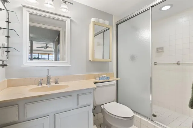a bathroom with a toilet a sink a mirror a shower and vanity
