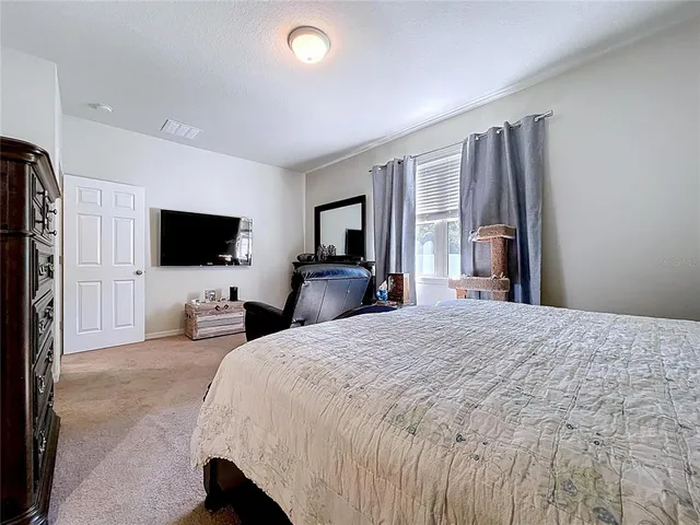 a bedroom with a bed and a flat tv screen on wall