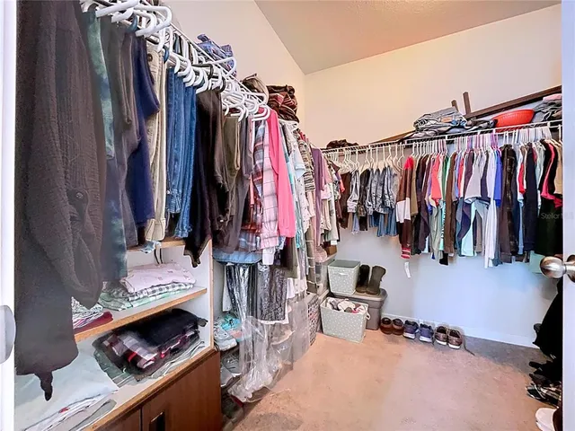 a view of walk in closet with clothes and shoes