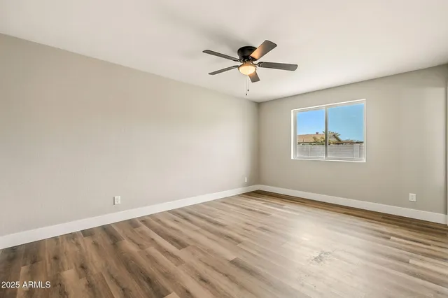 a view of empty room with wooden floor and fan