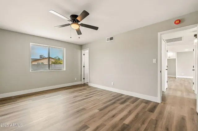 a view of an empty room with window and wooden floor