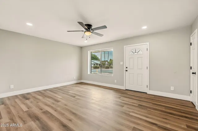 a view of an empty room with wooden floor and a window