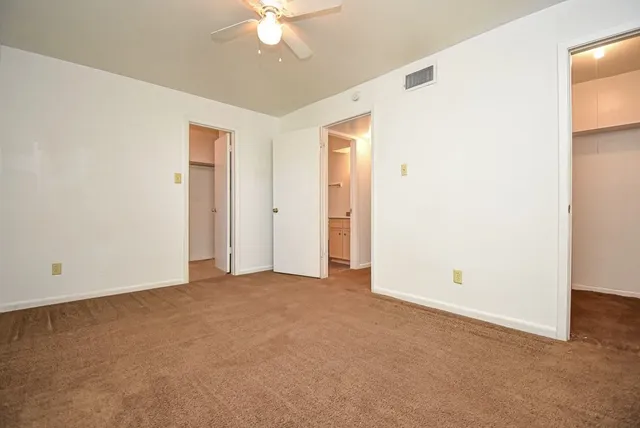an empty room with a chandelier fan and a window