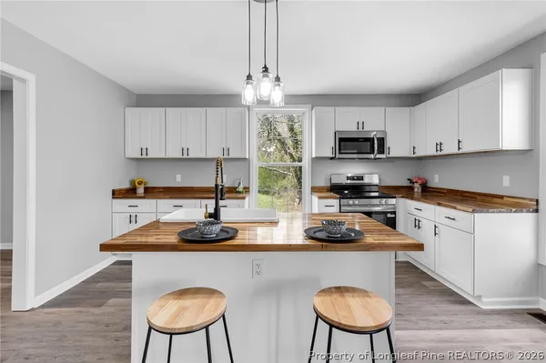 a kitchen with stainless steel appliances a dining table chairs a sink and white cabinets