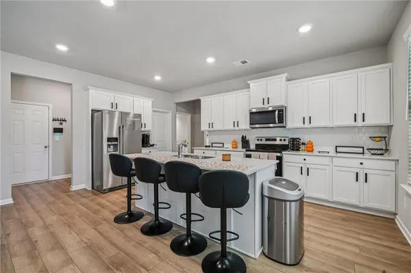 a kitchen with stainless steel appliances granite countertop a refrigerator a stove a sink dishwasher and white cabinets with wooden floor