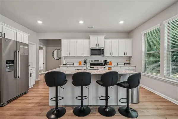 a kitchen with stainless steel appliances a dining table chairs refrigerator and sink