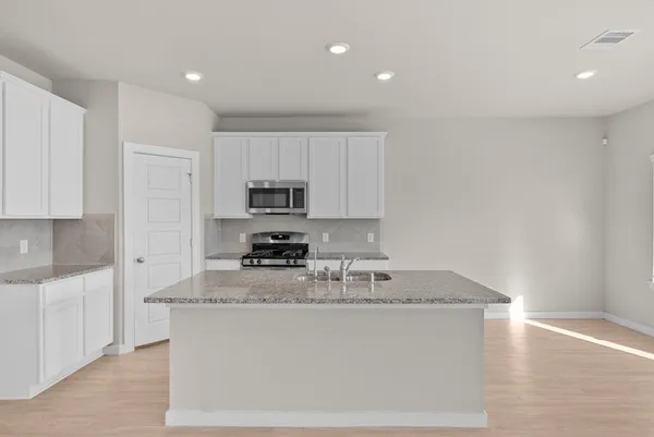a kitchen with stainless steel appliances granite countertop a sink stove and microwave