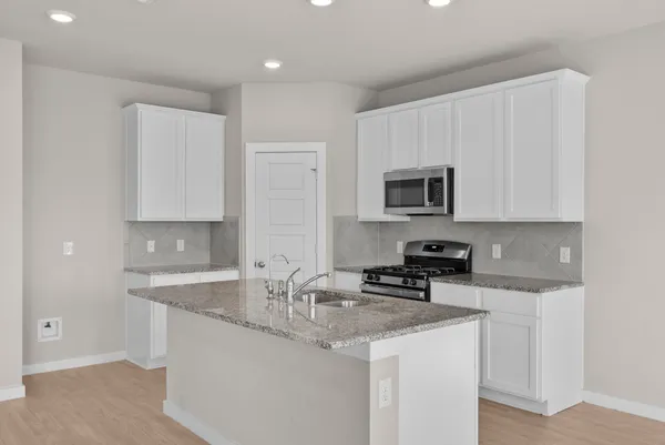 a kitchen with granite countertop a sink a stove and cabinets