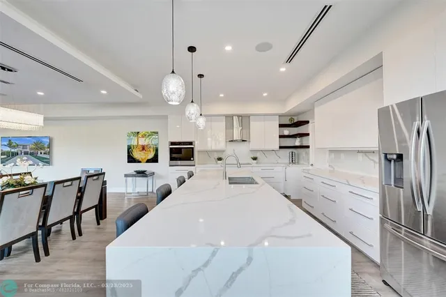 a large kitchen with stainless steel appliances kitchen island a table chairs refrigerator and a sink