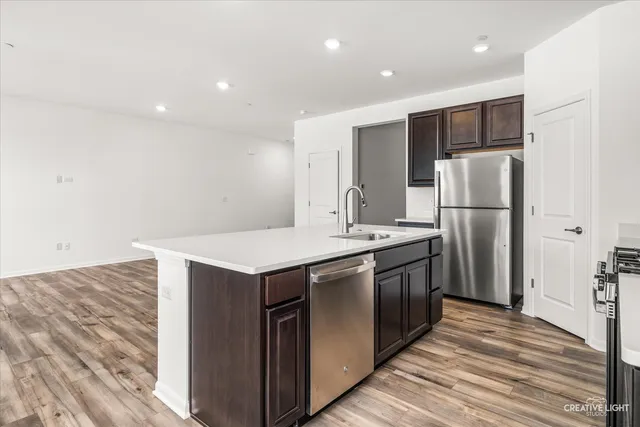a kitchen with kitchen island a sink stainless steel appliances and refrigerator