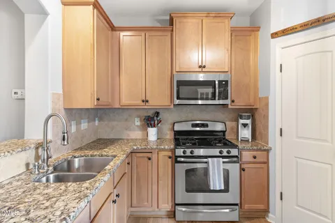 a kitchen with granite countertop a refrigerator stove and sink