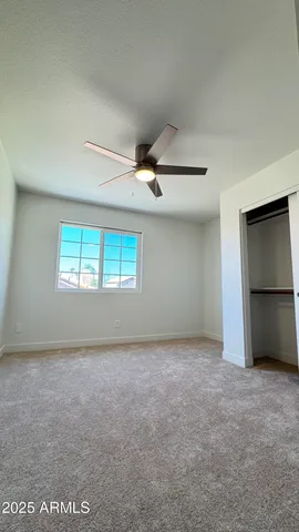 an empty room with windows and ceiling fan