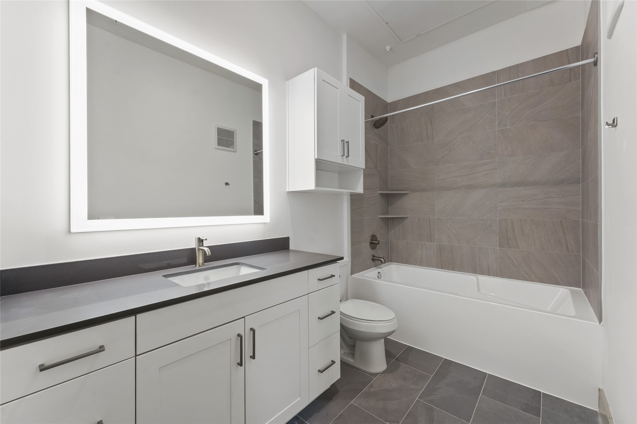 170 Malone Street, Unit 3401 Houston, TX 77007 - Photo 5 of 28 This modern bathroom features a spacious vanity with a large, illuminated mirror. The shower-tub combo is accented with elegant wall tiles and built-in shelving. The overall design is clean and contemporary, offering a bright and functional space.