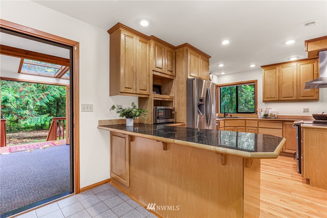 17418 Southeast 106th Street Renton, WA 98059 - Photo 13 of 39 a kitchen with stainless steel appliances granite countertop a refrigerator a stove and a sink with wooden cabinets