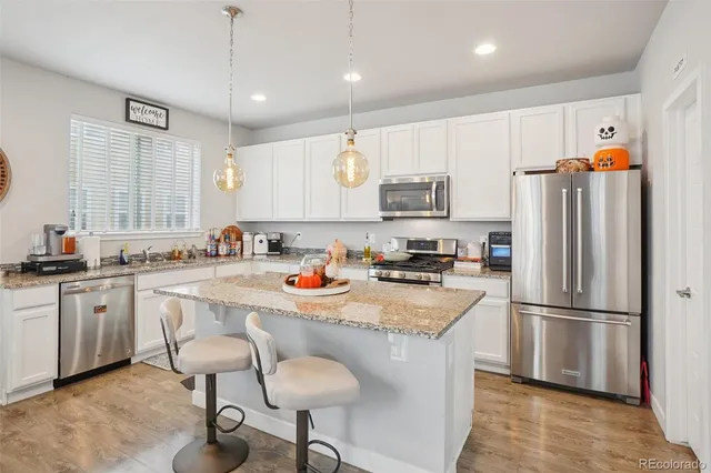 a kitchen with stainless steel appliances granite countertop a refrigerator a sink a stove a dining table and chairs