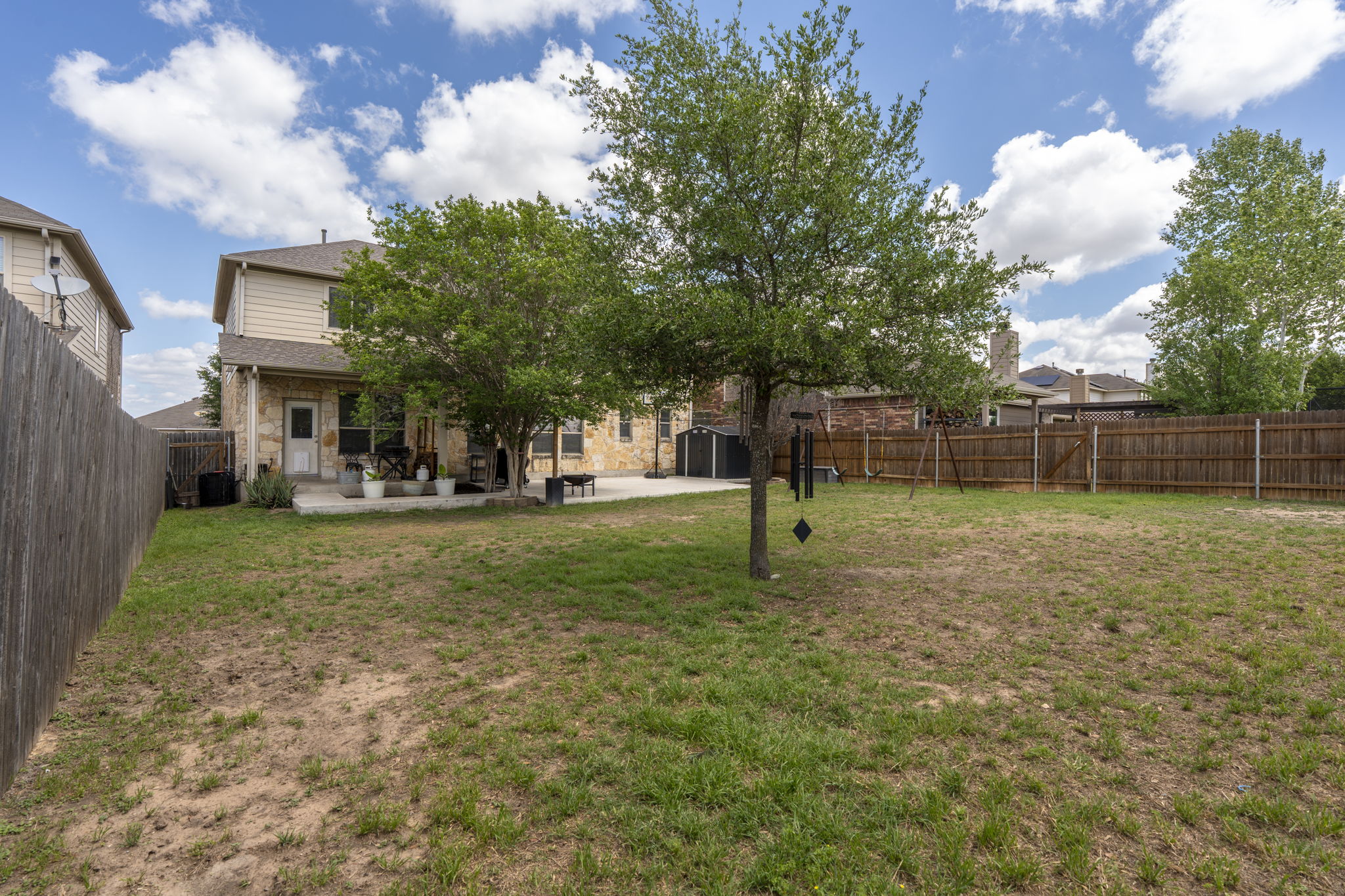 227 Sandstone Trail Buda, TX 78610 - Photo 24 of 33 Expansive backyard featuring a partial wood privacy fence, mature trees, and a concrete patio