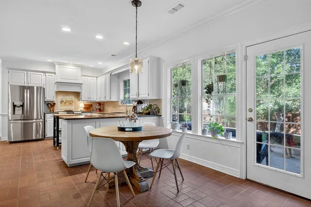 a kitchen with stainless steel appliances kitchen island a table chairs and a wooden floor