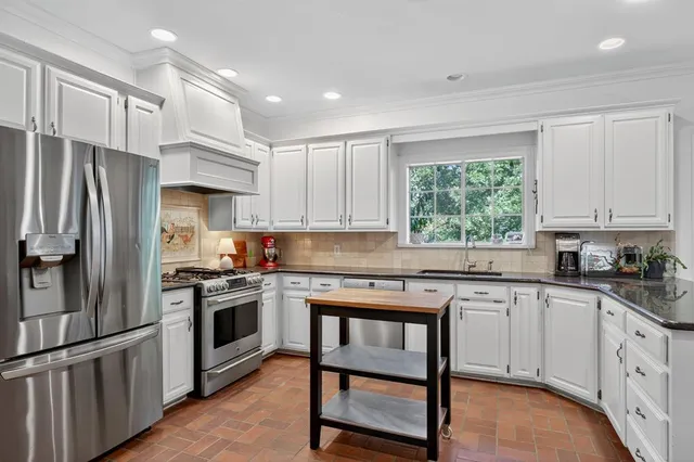 a kitchen with white cabinets stainless steel appliances and a window