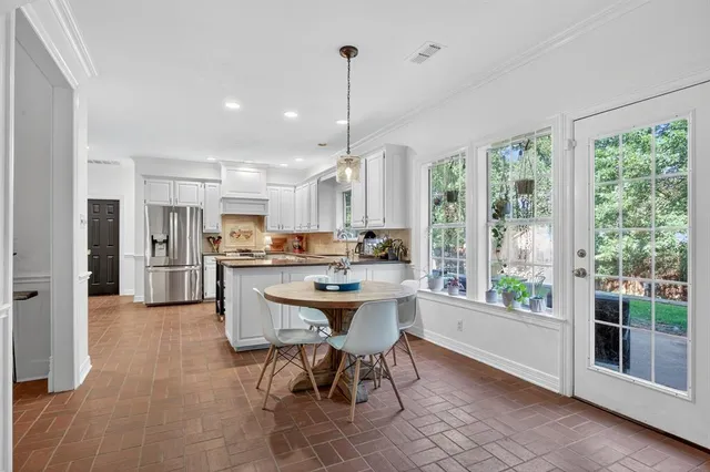 a dining hall with stainless steel appliances granite countertop a refrigerator a sink a dining table and chairs