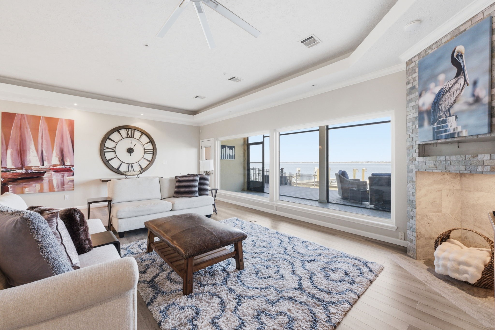 2 Regency Point Montgomery, TX 77356 - Photo 3 of 43 Spacious living area with tray ceilings, wood-look flooring, and a striking fireplace enclave, all framed by expansive windows with stunning open water views.