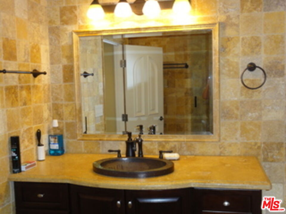 1880 Veteran Avenue, Unit 107 Los Angeles, CA 90025 - Photo 11 of 26 a bathroom with a granite countertop sink a mirror and shower